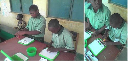 (Left to right) S. I., grade 5 and B. W., grade 6 carry out keyboard repairs on some XOs.